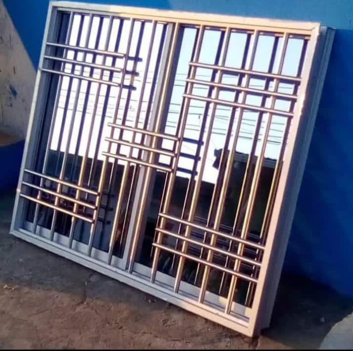 Ventana de aluminio natural con reja de seguridad en cruz